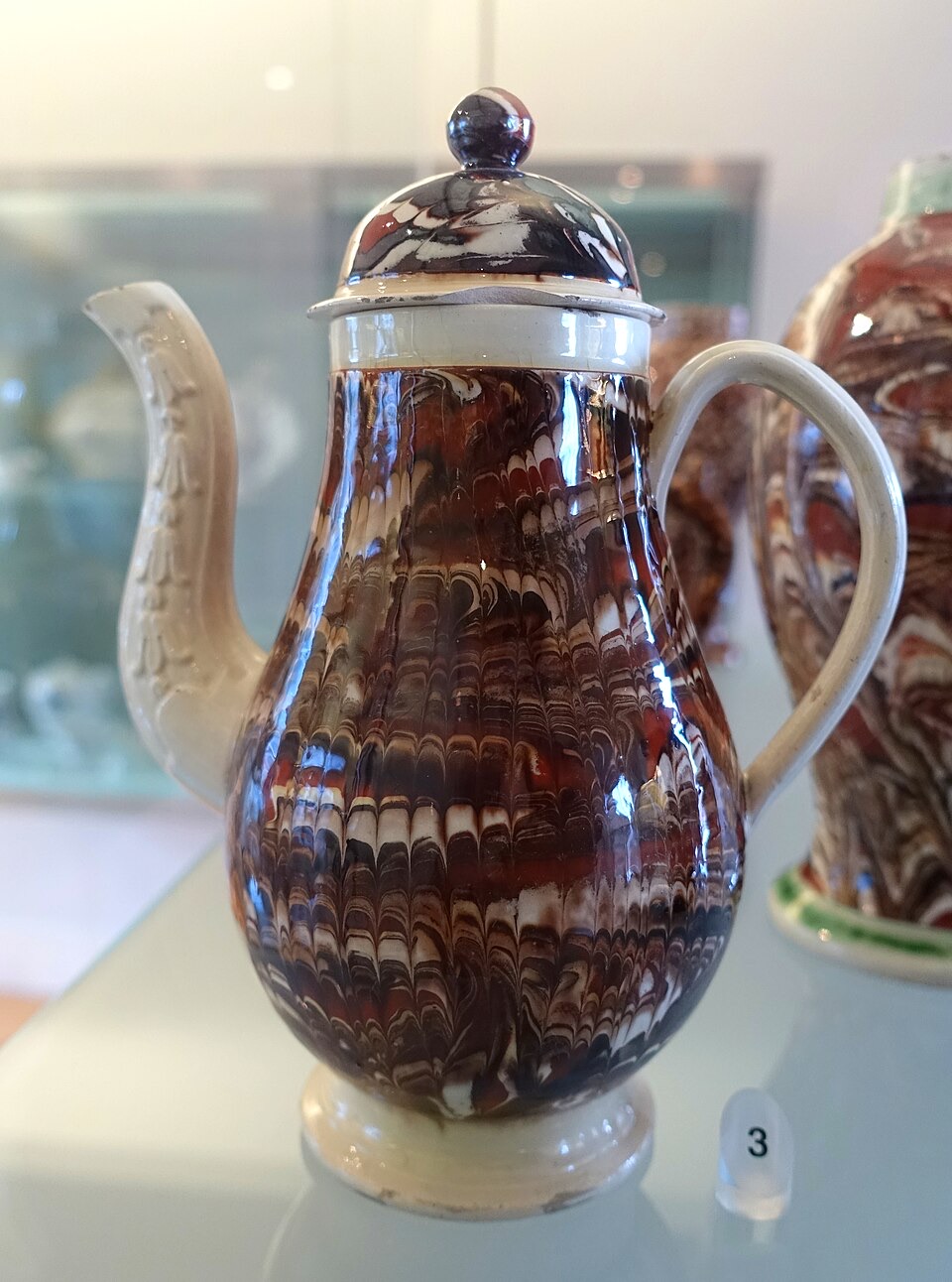 A coffee pot with a rich brown, cream, and dark marbled agateware pattern running through the whole vessel body