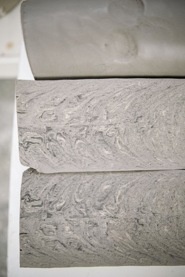 Close-up of raw, grey plastic clay blocks with visible wedging texture