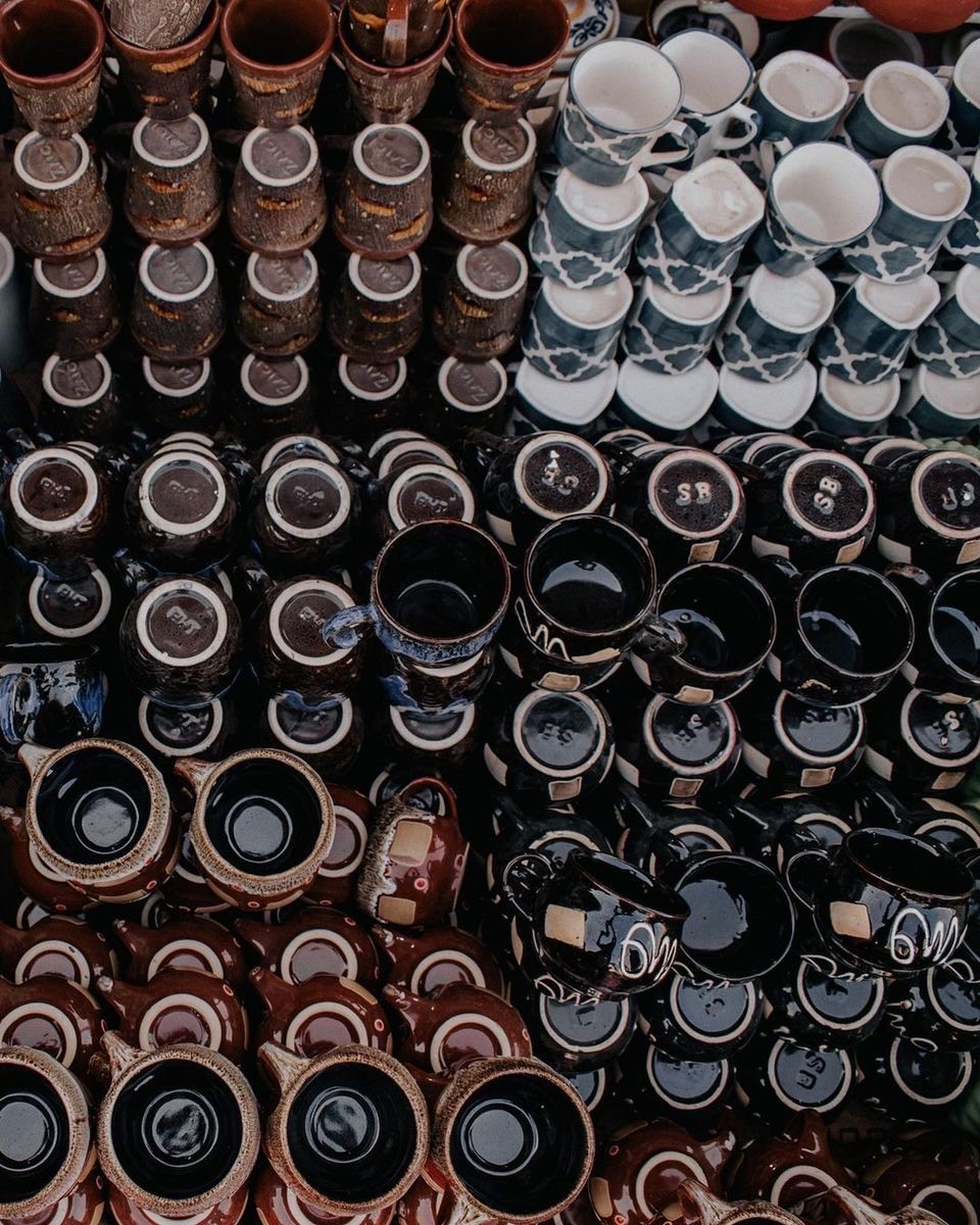 Rows of glazed ceramic mugs with consistent, even glaze color at a market display