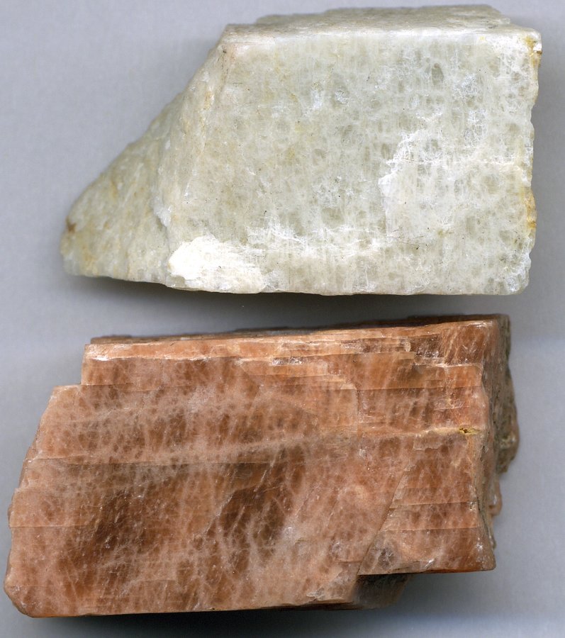 Two raw potassium feldspar mineral specimens, one pale cream and one salmon-pink