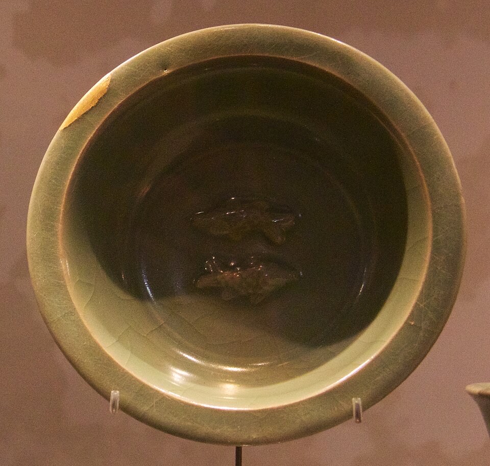 A green-glazed celadon bowl, the glaze pooling darker green in the interior