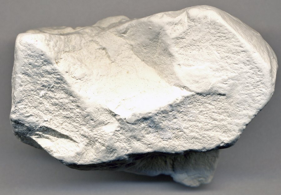 A pale, off-white lump of raw kaolinite specimen