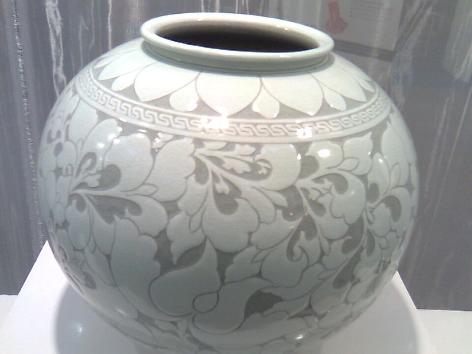 A large Korean buncheong jar with a white slip-inlaid floral scroll pattern covering its rounded body
