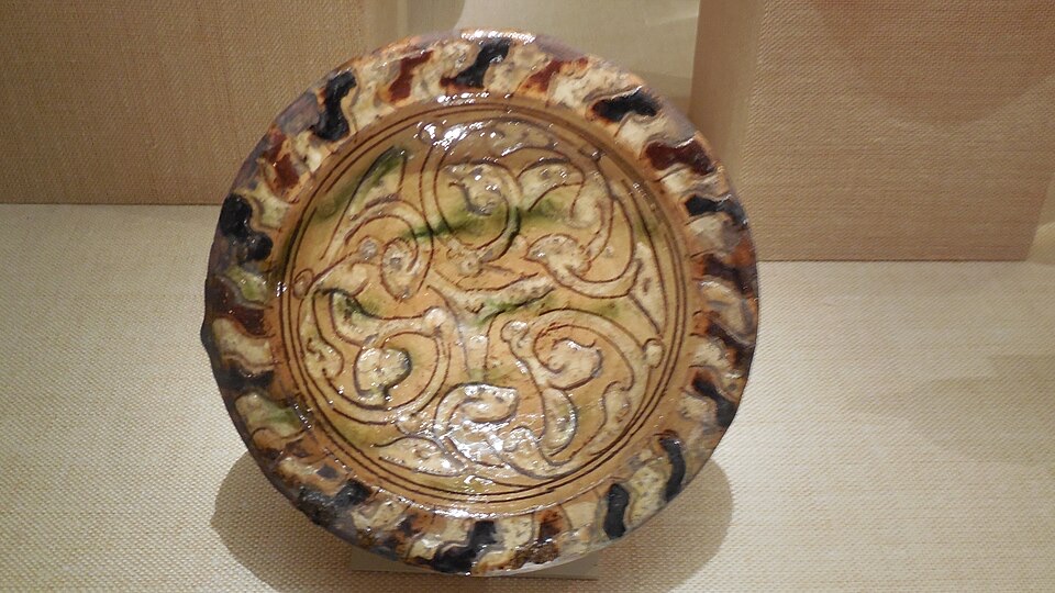 A 14th-century Mamluk sgraffito bowl with a swirling design incised through a white slip layer to the reddish body beneath