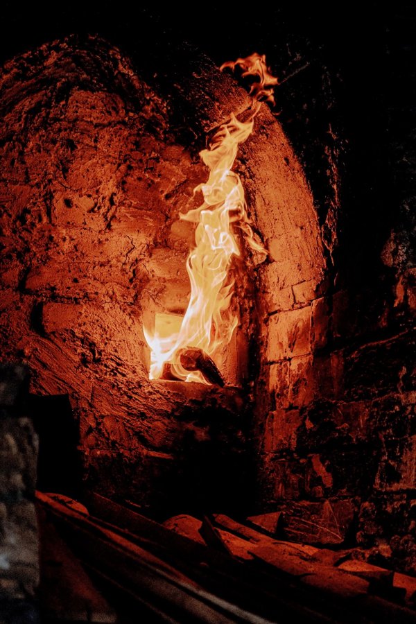 A traditional brick kiln with flames shooting through a stoke hole during active firing